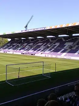 Photographie montrant un but, le terrain et une tribune du stade avec l'inscription « BEERSCHOT » sur les sièges.