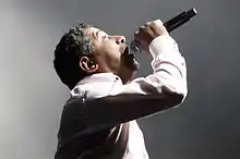 Photo d'un chanteur en chemise devant un micro.