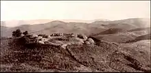 Photographie d'un groupe de huttes disposées en cercle au sommet d'une colline.