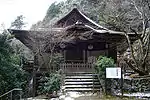 Vue frontale d'un bâtiment en bois avec des murs blancs et pignons ondulés en ligne avec les avant-toits et au-dessous d'un pignon normal.