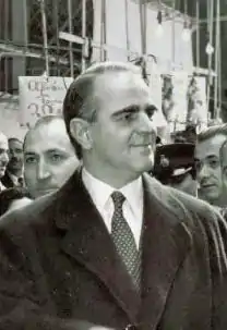 Photographie en noir et blanc d'un homme en costume dans une manifestation.