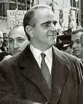 Photographie en noir et blanc d'un homme portant un manteau et une cravate.