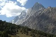 Photographie en couleur, montrant une montagne, vue depuis une vallée