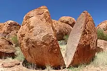 Une énorme pierre toute ronde cassée en deux par le milieu.