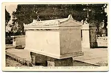 Photographie ancienne d'un sarcophage dans une cour avec d'autres artefacts archéologiques
