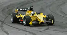 Une monoplace de F1 jaune, vue de trois-quarts, prend un virage à gauche.