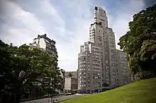 Photographie d'un bâtiment aux contours arrondis avec un parc au premier plan