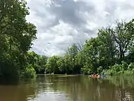 Deux canoës-kayaks sur une rivière bordée d'arbres.