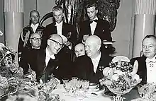 Photographie de plusieurs hommes en tenue de soirée assis lors d'un banquet