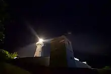 La tour élancée, ronde, lumineuse, du phare. Devant, une tour carrée, massive, obscure. Au loin, les étoiles.