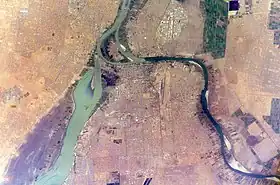 Vue aérienne de la zone de confluence des Nil Bleu et Blanc. Khartoum est située au centre et en bas, Omdourman à gauche et Bahri à droite, chacune sur une rive. L'île Tuti est visible au centre du confluent, entre les trois villes.