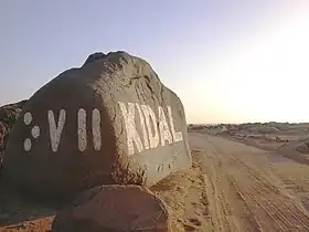Signalisation bilingue à l'entrée de Kidal. Sur le côté gauche du rocher, Kidal est écrit en caractères tifinagh « ⴾⴸⵍ ».