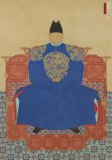 Peinture du roi Taejo, assis sur son trône de face. Il porte un large vêtements avec des motifs sur le ventre et sur les épaules, ainsi qu'un chapeau.