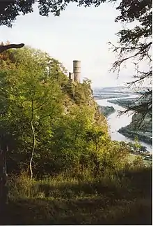 À-pic rocheux au sommet duquel est une tour. Il surplombe une vallée où sinue une rivière.