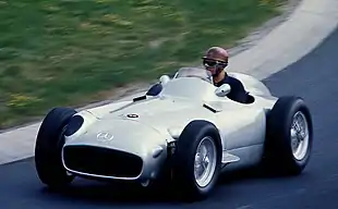 Photo de Karl Kling pilotant une Mercedes-Benz W196 sur une piste.