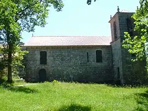 Photographie de la façade latérale d'ue église dominée par un clocher carré.