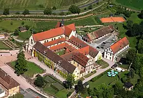 Photographie aérienne d'une abbaye. L'église est au second plan, les jardins et le réfectoire au premier plan, le cloître et les autres bâtiments conventuels au centre.