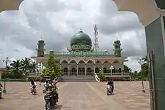Le parvis est richement décoré avec seulement 3 motos y circulant. La mosquée est constituée de 2 tours sur les côtés et un dôme central de couleur verte.