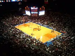 The inside of an arena with large scoreboard visible, which is set up for basketball.