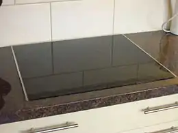 Une plaque noire sur un comptoir de cuisine. Quatre ronds blancs sont distinguables, représentant les plaques à induction.