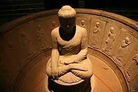 Photographie d'une statue en pierre d'un bouddha assis en tailleur.