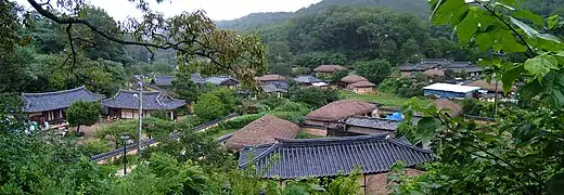 Photographie d'une village ancien, les toitures sont pour l'essentiel tout ce qui est visible, et le tout est entouré de verdure.
