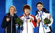 Trois concurrentes présentant leur médaille et un bouquet.