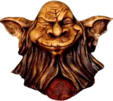 Sculpture en bois de la tête d'une créature chauve avec de grandes oreilles et une longue barbe