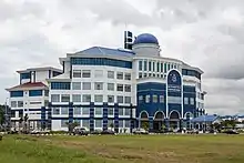 Photographie d'un bâtiment bleu et blanc sur lequel est inscrit « Ibu Pejabat Polis Kontinjen Sabah ».