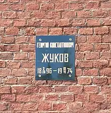 Photo en couleur d'une plaque fixée sur un mur de briques rouges.
