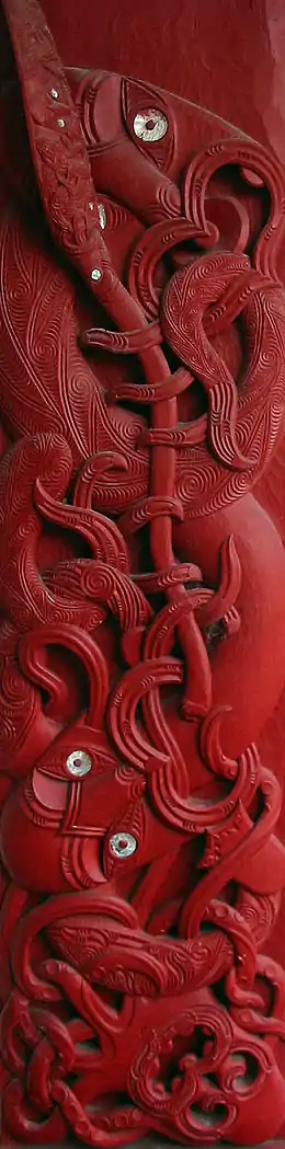 Sculpture de bois peint en rouge représentant une pieuvre combattant un homme doté d'une longue lance.