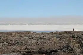 Photographie de Kvitoya, regardant vers le haut des montagnes depuis l'étroite bande de plage rocheuse. Elle fut prise juste à gauche du monument d'Andrée.