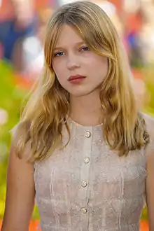 Photographie au format portrait et en couleurs d'une jeune fille blonde sur un tapis rouge.