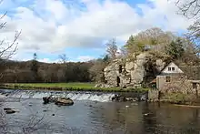 Un moulin à gauche, entouré de falaises.