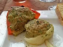 Un oignon et une tomate farcis, dans une assiette.