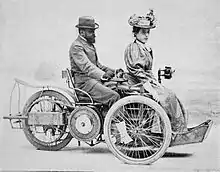 Photo d'un couple assis sur un véhicule à trois roues.