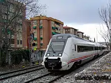 la photo couleur montre une rame à l'arrêt en sortie de dépôt. Le capot ouvert montre un attelage central et les rétroviseurs sont déployés.