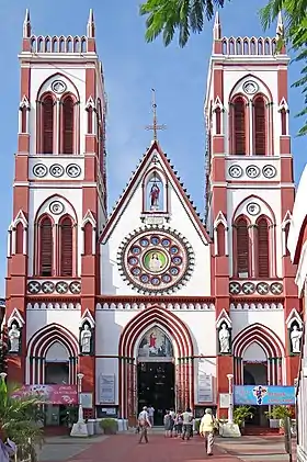 Photographie couleur d’une église aux formes néo-gothiques mais en couleur rouge et blanc, faisant ressortir chaque élément de façade.