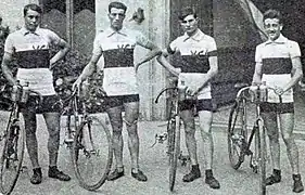 Photo de quatre hommes posant côte-à-côte et tenant leurs vélos de course respectifs.