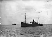 Photographie en noir et blanc de deux navires, au premier plan sur la droite, à l'arrière-plan sur la gauche.