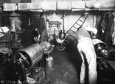 Photographie en noir et blanc d'ouvriers travaillant sur des cylindres.