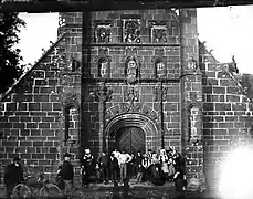 Personnages en costume breton devant l'église paroissiale vers 1900.