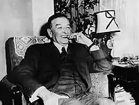 Photographie noir et blanc d'un homme d'un homme souriant avec un cigare aux lèvres.