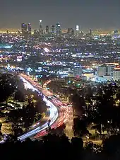 Photographie du centre-ville de Los Angeles vu depuis des collines éloignées, la nuit.