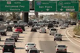 Plusieurs voitures arrêtées sur une autoroute. Les panneaux indiquent Hollywood Freeway, Ventura, South San Pedro et Pasadena.