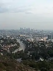 Photographie du centre-ville de Los Angeles vu depuis des collines éloignées, sous un ciel nuageux.