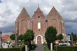 Façade de l'église Saint-Omer de Ledringhem, montrant le style hallekerque, avec nef à trois vaisseaux juxtaposées.