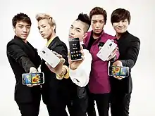Photographie de cinq jeunes hommes en tenues à la mode, montrant chacun un smartphone
