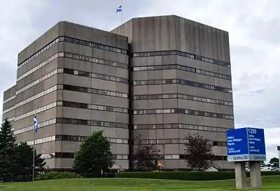 Photographie d'un immeuble gris d'une dizaine d'étage composé de deux tours contigües