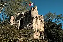 Vue en contre-plongée du petit château médiéval à l'aspect ruiné avec ses échauguettes, son pont levis.